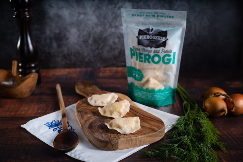 A bag of Vegan Cheeze and Potato Pierogi and some pierogi on a cutting board