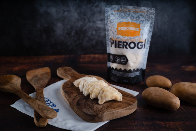 A bag of Coconut Bac'n and Potato Pierogi and some pierogi on a cutting board