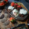 Chocolate-dipped strawberry pierogi and fresh strawberries served on a plate with pierogi-shaped chocolates